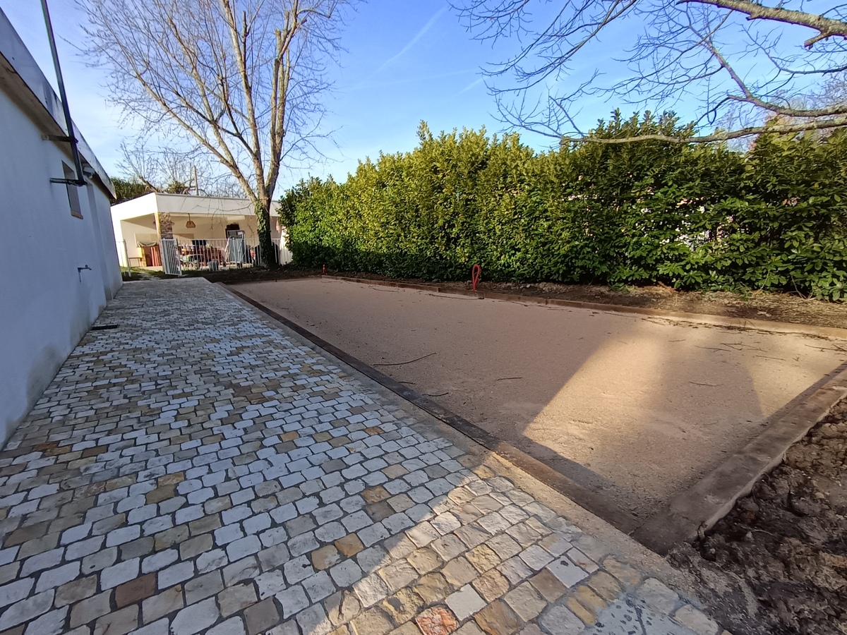 Réalisation du terrain de pétanque -Mise en œuvre d'un géotextile, 0/20 c , castine en 0/4 beige, tour du terrain en traverse bois de Chêne, traitement autoclave, classe 4