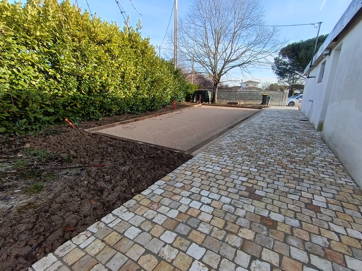 Réalisation du terrain de pétanque -Mise en œuvre d'un géotextile, 0/20 c , castine en 0/4 beige, tour du terrain en traverse bois de Chêne, traitement autoclave, classe 4